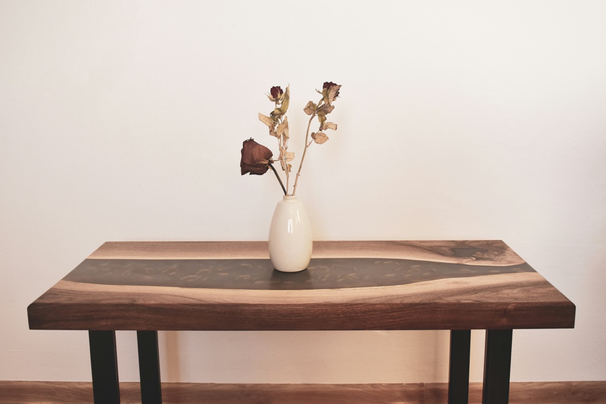 Elegant wooden table with vase of fresh flowers showing beautiful wood grain and polished epoxy finish