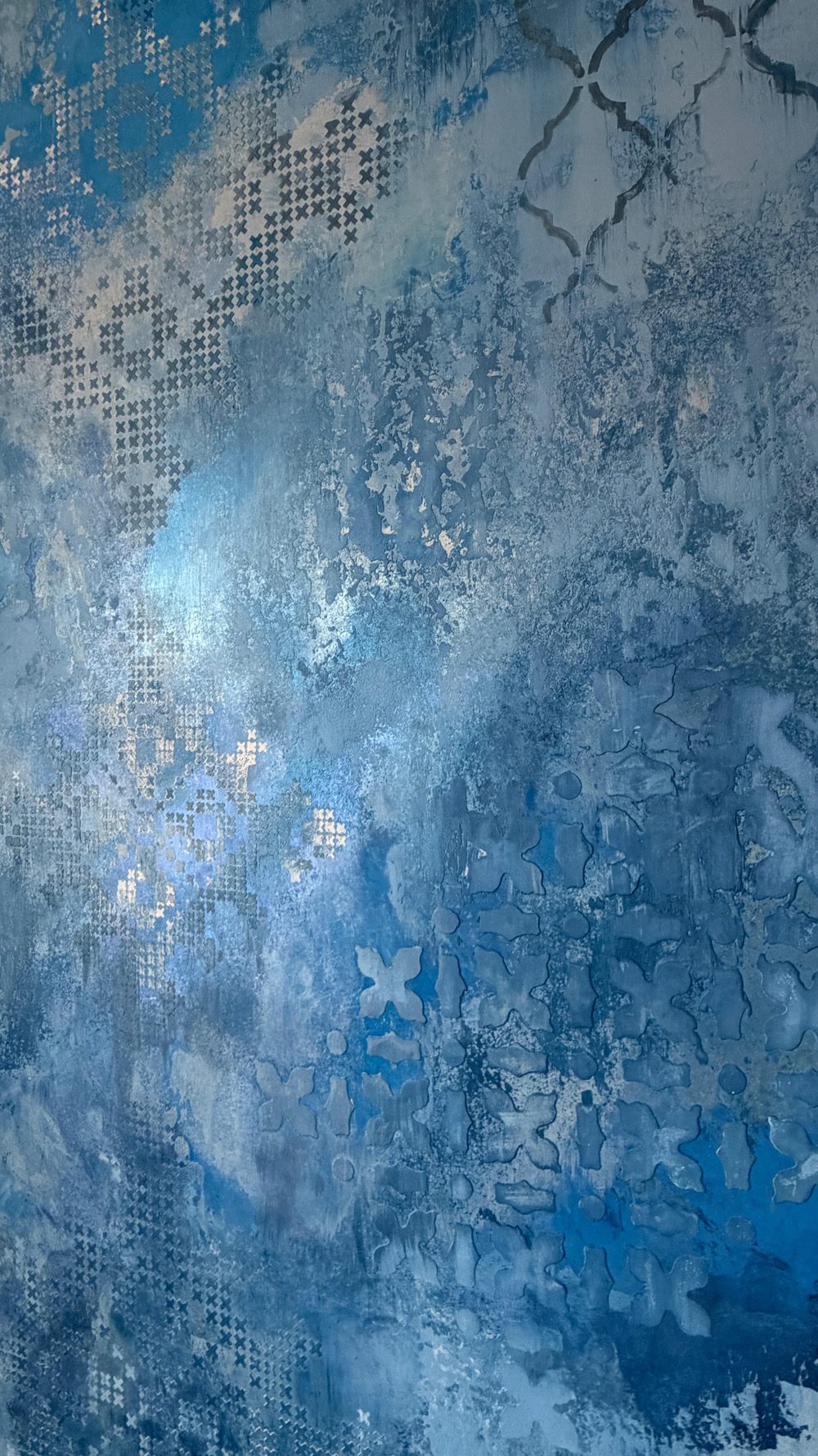 Deep blue Marmorino stucco bedroom feature wall with cloudy water-like movement, pearlescent sheen and subtle cross-stitch and Moroccan quatrefoil stencil patterns