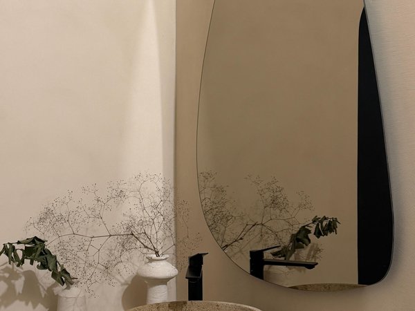 Organic minimalist microcement bathroom with stone vessel sink, asymmetric mirror and wabi-sabi styling